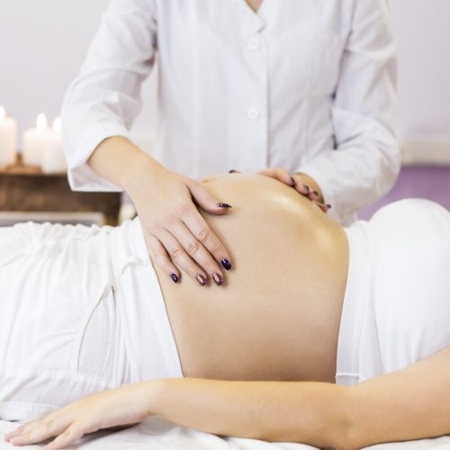 Young pregnant woman have massage treatment at spa salon